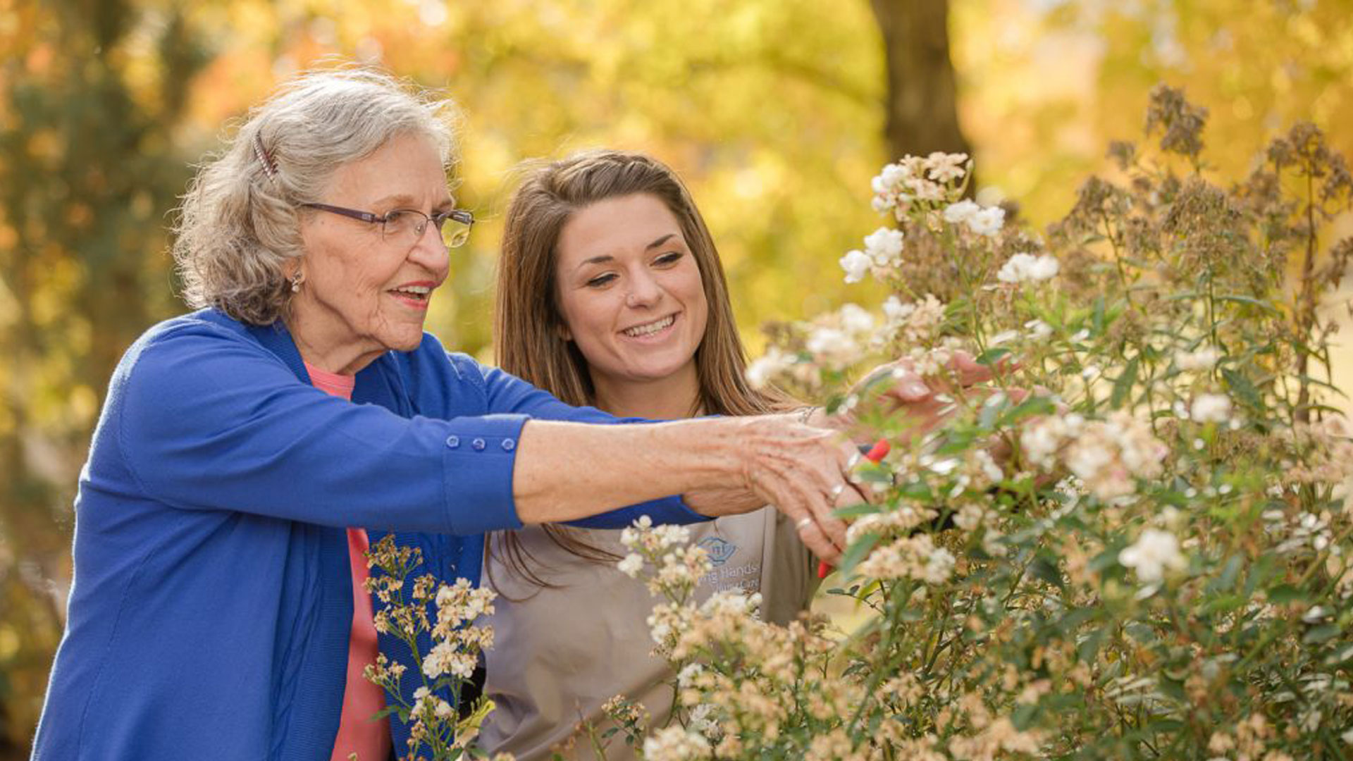 An elderly woman and her caregiver working together in a garden, symbolizing fostering independence and autonomy for seniors with the support of caregivers.