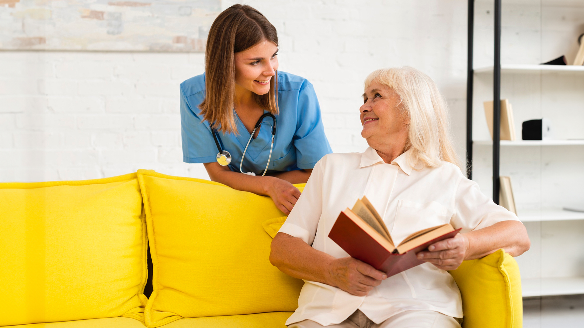 A caregiver and their client, a person with dementia, are sitting together and reading a book. The image illustrates the therapeutic benefits of storytelling for individuals with dementia, promoting engagement and connection through shared narratives.