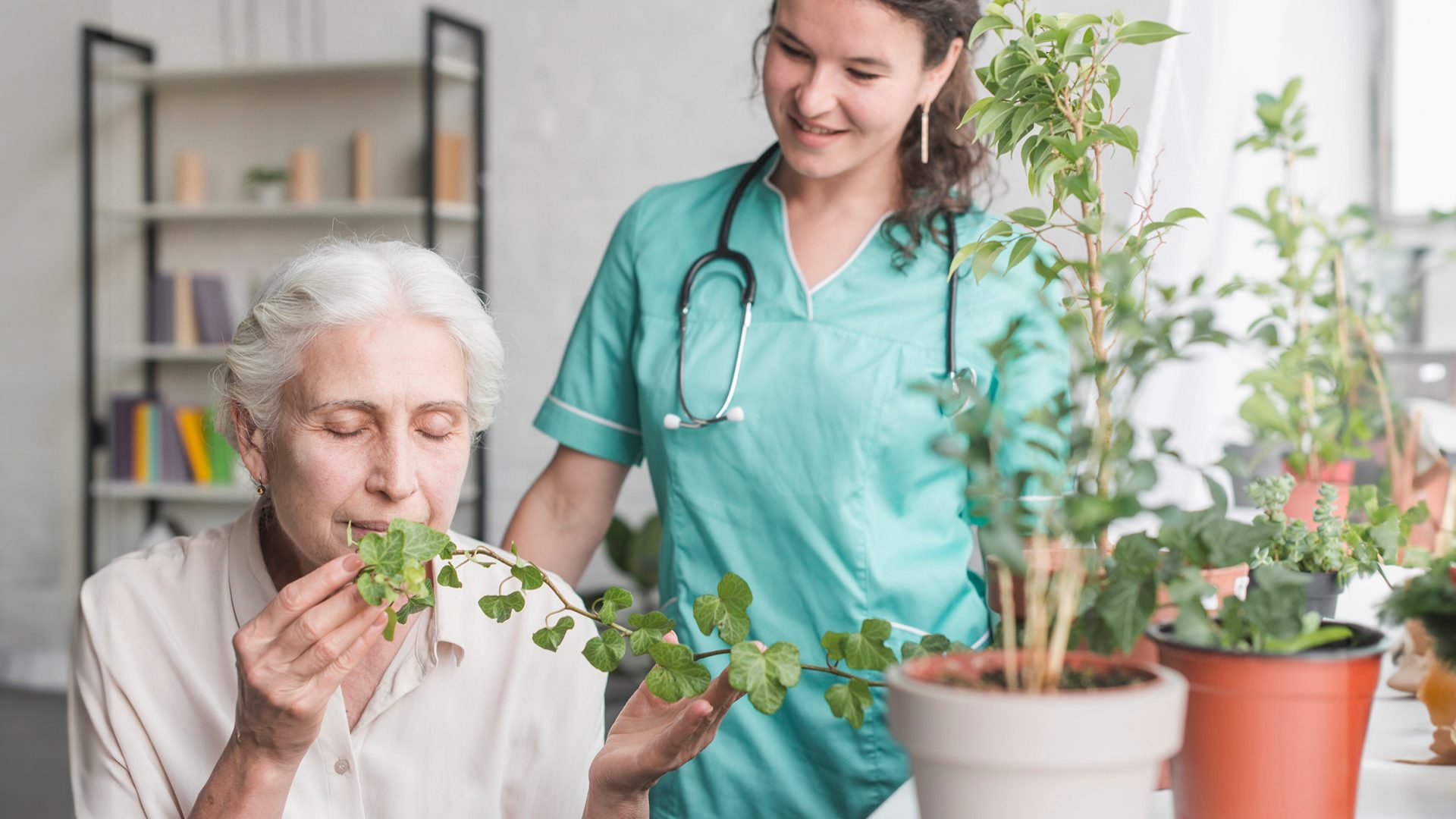 A caregiver and their client, a person with dementia, are seen tending to a plant in a garden. The image illustrates the therapeutic benefits of gardening for individuals with dementia, promoting relaxation and sensory stimulation.